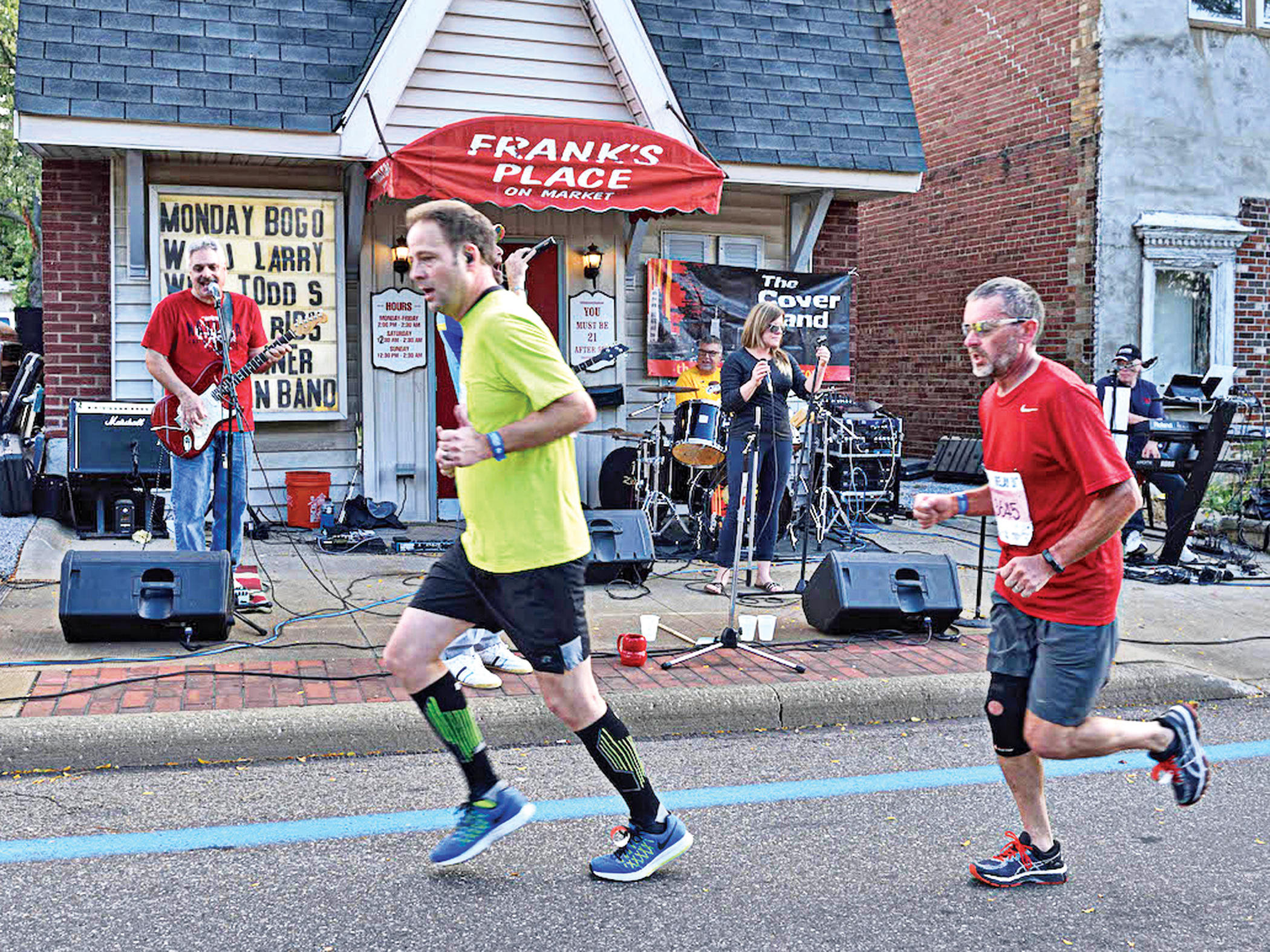 Runners in Highland Square run past a band performing